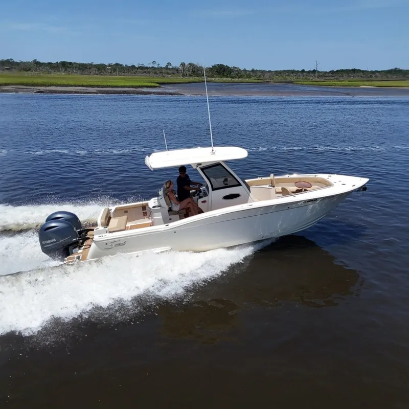 Slide: The Image of 2021 Scout 277 LXF boat cruising on a calm river under a clear blue sky. - 0