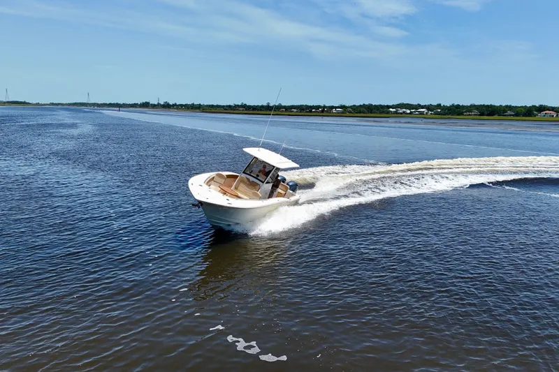 Slide: The Image of 2021 Scout 277 LXF boat cruising on open water under clear blue skies. - 10