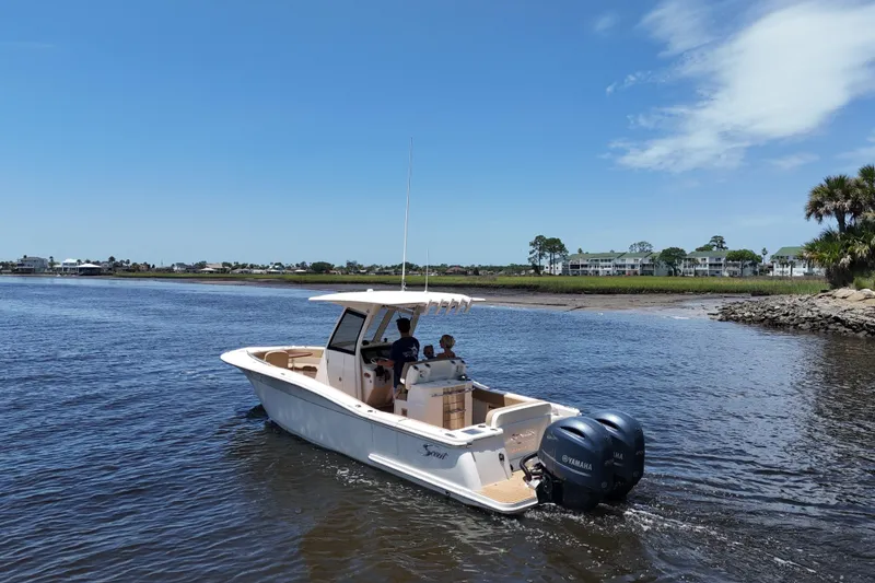 Slide: The Image of 2021 Scout 277 LXF boat cruising on a sunny day near the shoreline. - 15