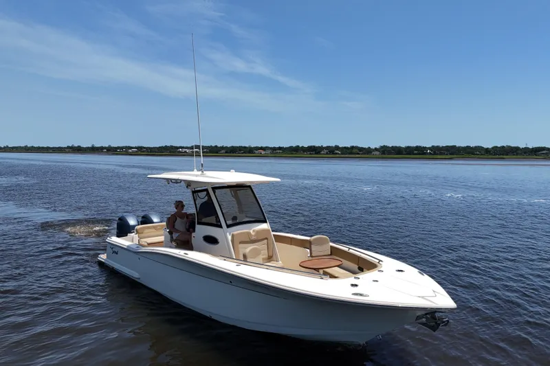 Slide: The Image of 2021 Scout 277 LXF boat cruising on a calm, scenic waterway. - 30
