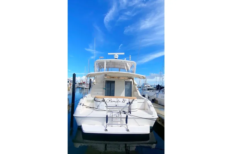 Slide: The Image of 1996 Sea Ray 440 Express Bridge yacht docked under clear blue sky. - 2