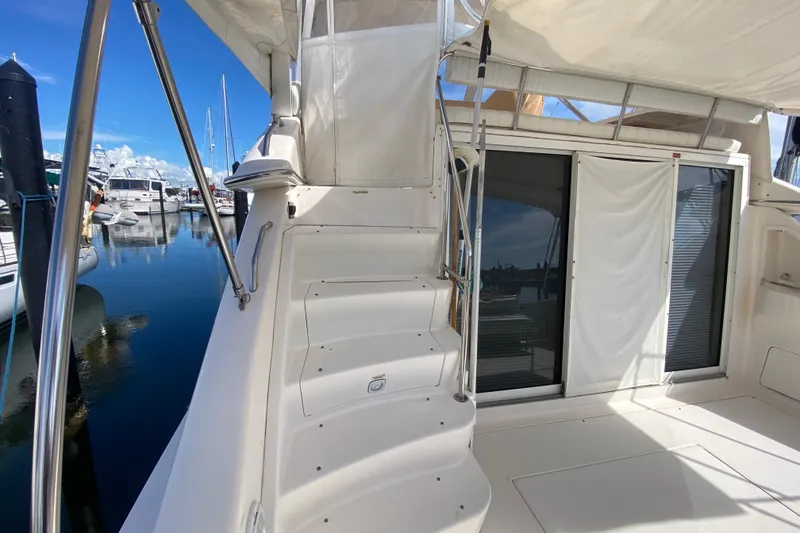Slide: The Image of 1996 Sea Ray 440 Express Bridge yacht interior with stairs and sliding doors at marina. - 36