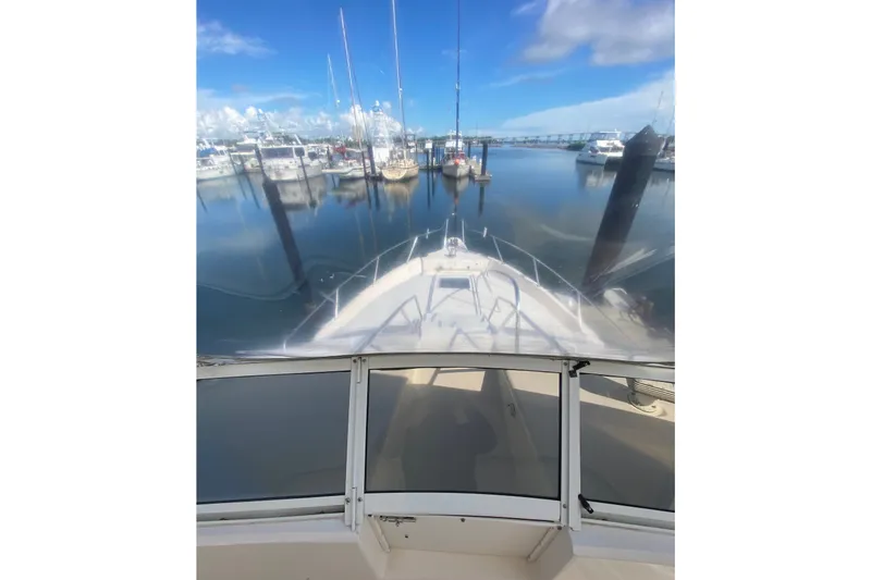 Slide: The Image of 1996 Sea Ray 440 Express Bridge yacht docked at a marina under clear blue skies. - 46