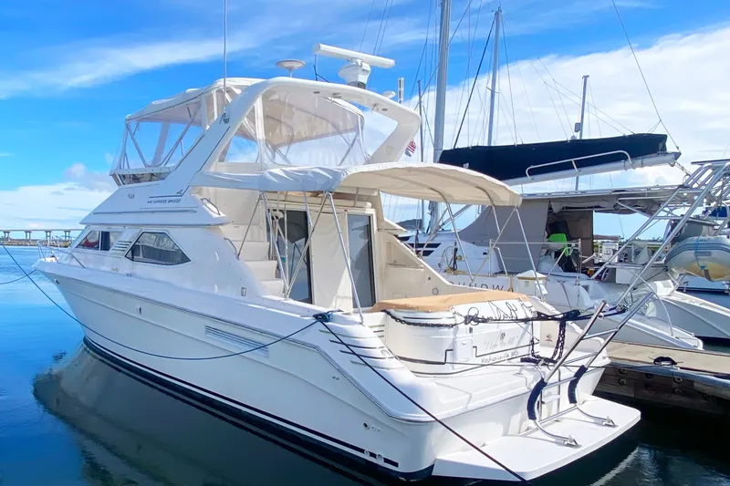 Slide: The Image of 1996 Sea Ray 440 Express Bridge yacht docked at marina under clear blue sky. - 1