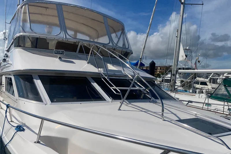 Slide: The Image of 1996 Sea Ray 440 Express Bridge yacht docked at marina under blue sky. - 7