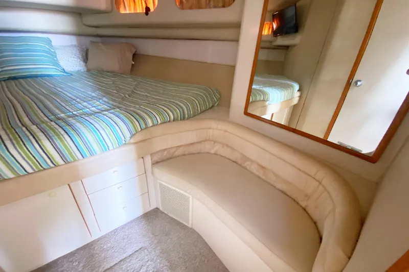 Slide: The Image of Interior cabin of 1996 Sea Ray 440 Express Bridge with bed, mirror, and seating area. - 26