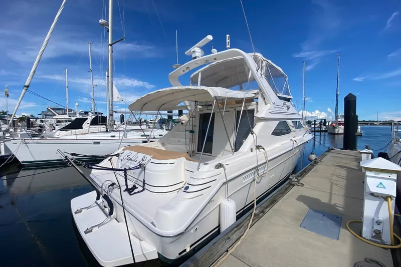 Slide: The Image of 1996 Sea Ray 440 Express Bridge yacht docked at marina under clear blue sky. - 3