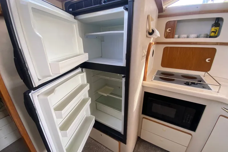 Slide: The Image of 1996 Sea Ray 440 Express Bridge kitchen with open fridge, stove, and microwave. - 19