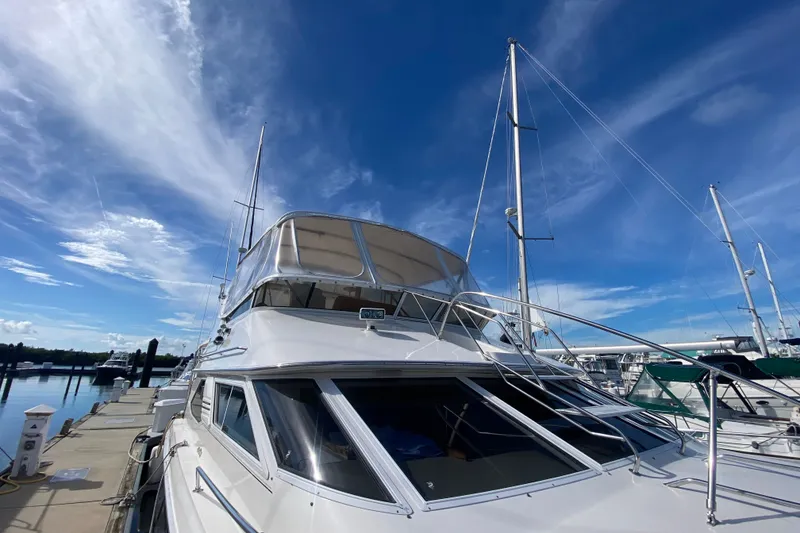 Slide: The Image of 1996 Sea Ray 440 Express Bridge yacht docked under a clear blue sky. - 5