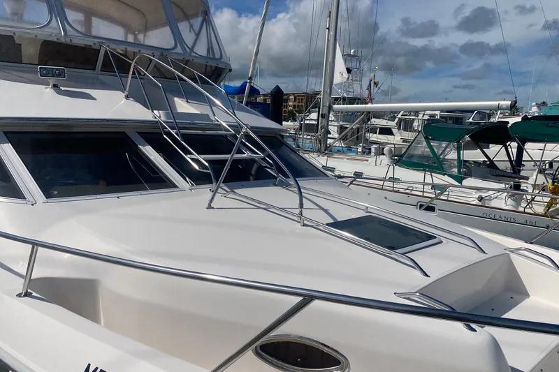 Slide: The Image of 1996 Sea Ray 440 Express Bridge yacht docked at marina under cloudy sky. - 8