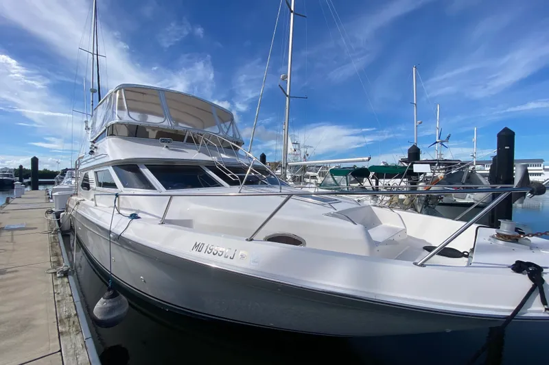 Slide: The Image of 1996 Sea Ray 440 Express Bridge yacht docked at marina under clear blue sky. - 4