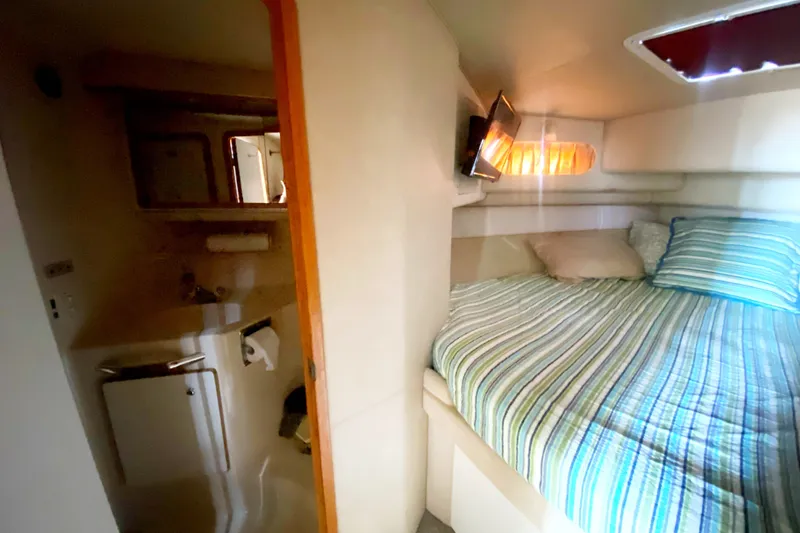 Slide: The Image of 1996 Sea Ray 440 Express Bridge cabin interior with bed and compact bathroom. - 28