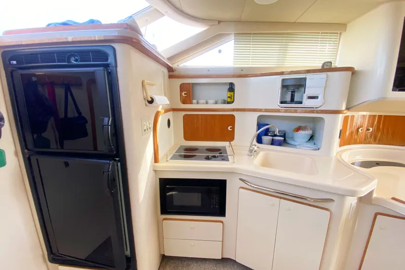 Slide: The Image of 1996 Sea Ray 440 Express Bridge kitchen with stove, microwave, and refrigerator. - 17