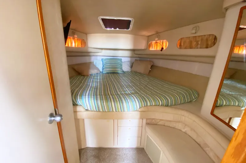 Slide: The Image of Cozy cabin interior of 1996 Sea Ray 440 Express Bridge with striped bedding. - 25