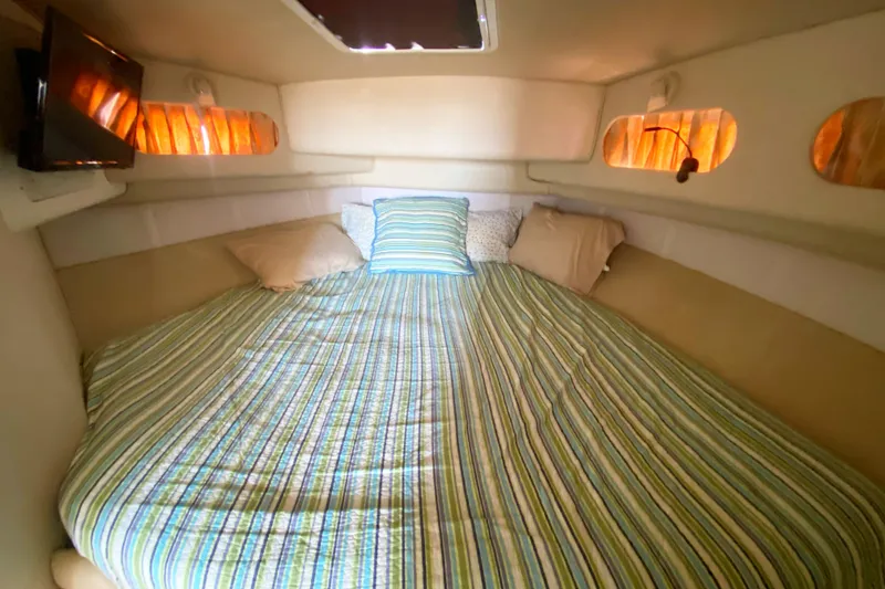 Slide: The Image of Cozy cabin interior of 1996 Sea Ray 440 Express Bridge with striped bedding and soft lighting. - 27