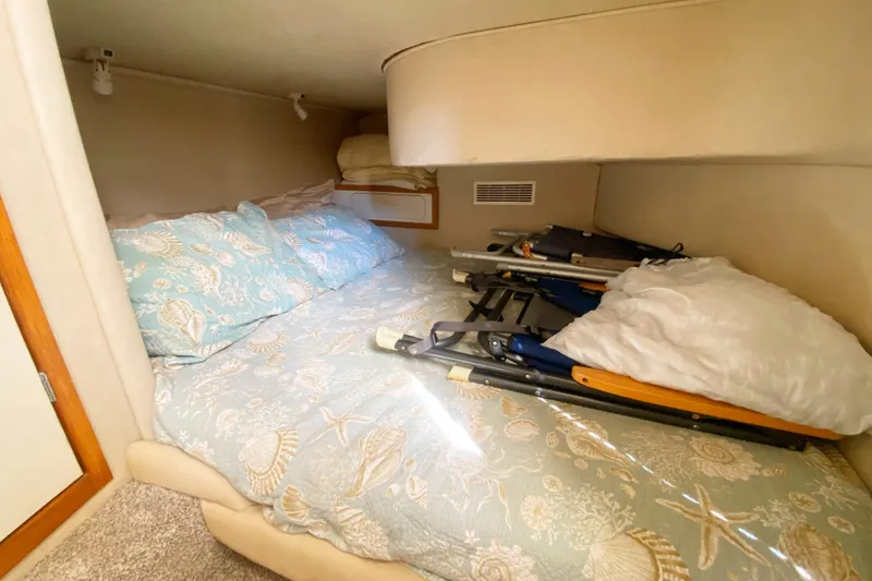 Slide: The Image of Cozy cabin interior of 1996 Sea Ray 440 Express Bridge with patterned bedding. - 31