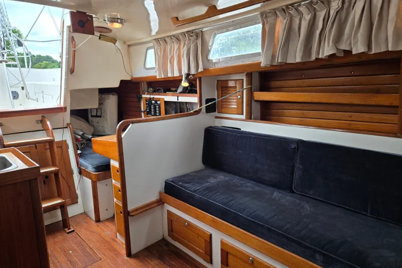 Slide: The Image of Interior of a 1978 Bristol 35.5 sailboat with wooden furnishings and navy cushions. - 27