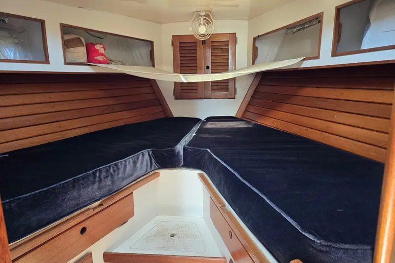 Slide: The Image of Interior cabin of a 1978 Bristol 35.5 sailboat with wooden accents and black cushions. - 18