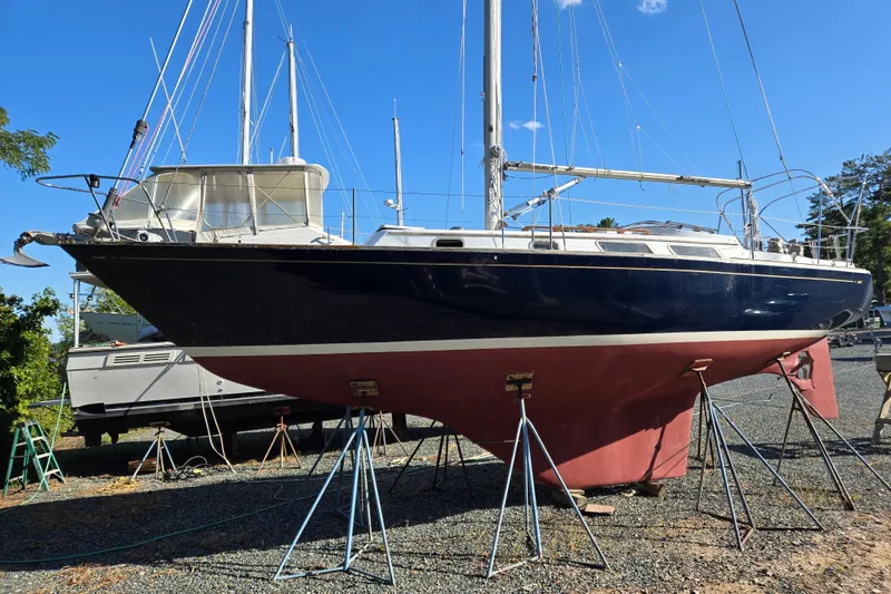Slide: The Image of 1978 Bristol 35.5 sailboat on stands, blue hull, white deck, clear sky background. - 35