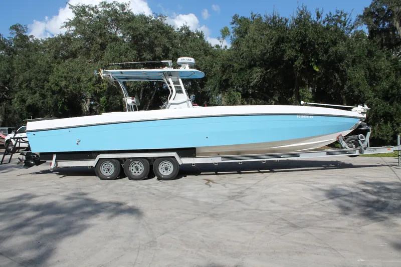 The Image of 2018 Lightning 38 Center Console boat on trailer, parked outdoors with trees in background. - 0