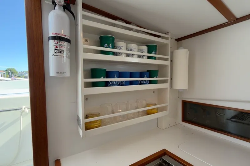 Slide: The Image of Interior of 1985 Holland 32 boat with shelves, cups, and fire extinguisher. - 39
