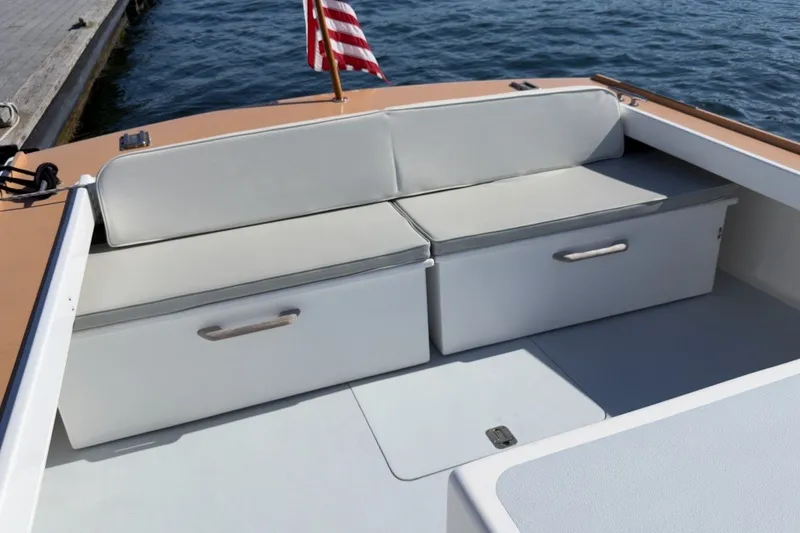 Slide: The Image of 1985 Holland 32 boat interior with cushioned seating and storage, docked by the water. - 15