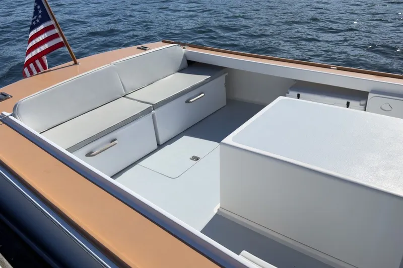 Slide: The Image of 1985 Holland 32 boat interior with white seating and American flag on calm water. - 13