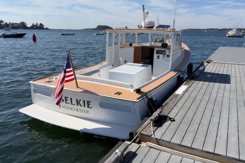 Slide: The Image of 1985 Holland 32 boat docked, displaying American flag, named "Selkie" in Manchester harbor. - 2