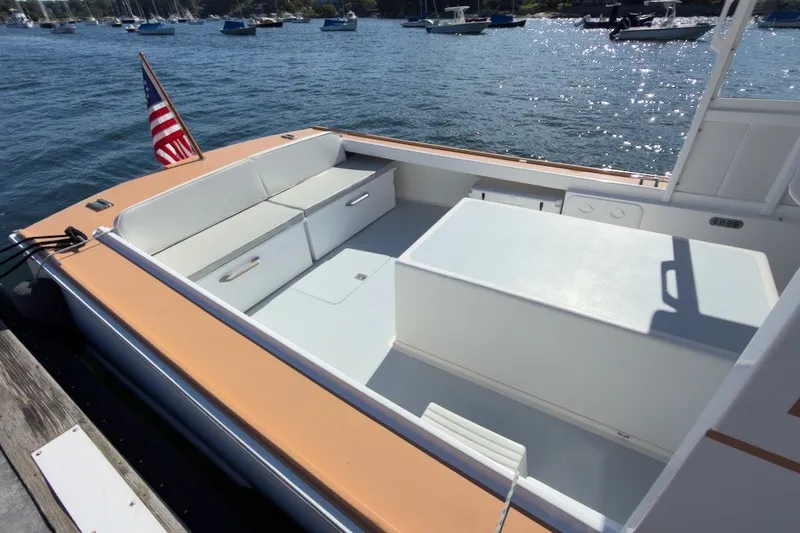 Slide: The Image of 1985 Holland 32 boat interior with seating, docked by the water, American flag displayed. - 10