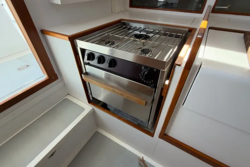 Slide: The Image of Compact kitchen area with a stainless steel stove and oven on a 1985 Holland 32 boat. - 36