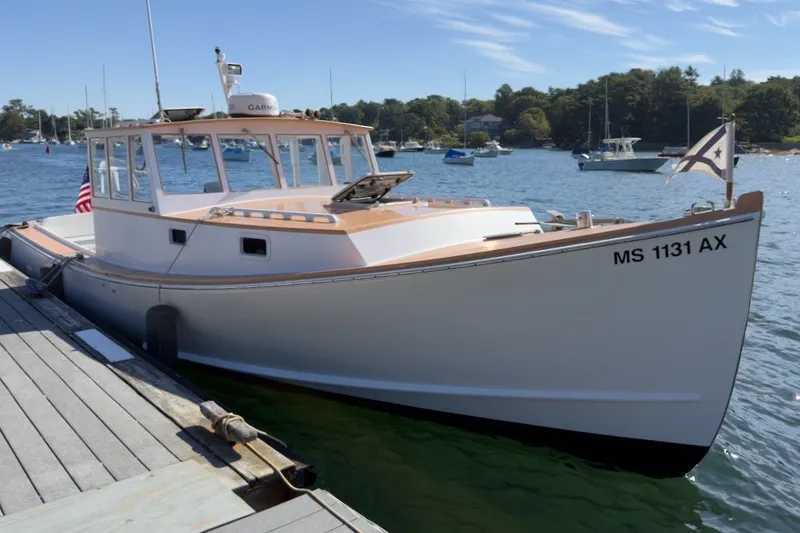 Slide: The Image of 1985 Holland 32 boat docked, displaying registration MS 1131 AX, with scenic harbor background. - 1