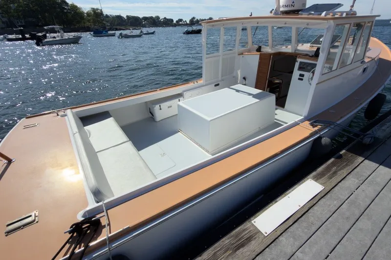 Slide: The Image of 1985 Holland 32 boat docked, featuring spacious deck and cabin, with scenic waterfront view. - 9