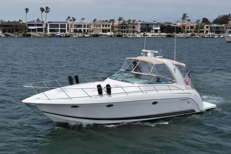Slide: The Image of 2003 Formula 40 PC yacht cruising on a calm waterfront with luxury homes in the background. - 6