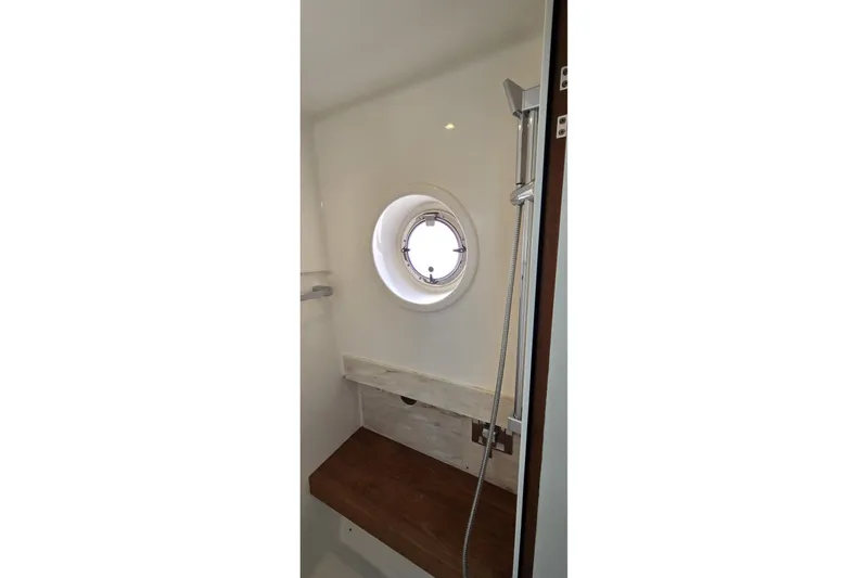 Slide: The Image of Interior of 2016 Tiara Yachts Q44 shower with porthole and wooden bench. - 69