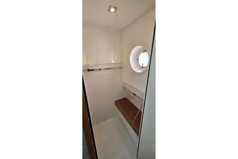 Slide: The Image of 2016 Tiara Yachts Q44 interior shower with porthole and wooden bench. - 68