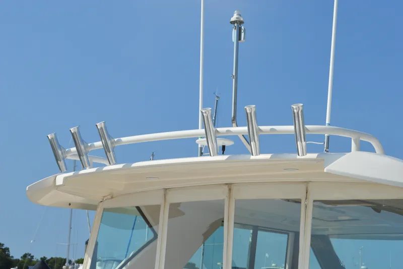 Slide: The Image of 2016 Tiara Yachts Q44 boat roof with rod holders against clear blue sky. - 25