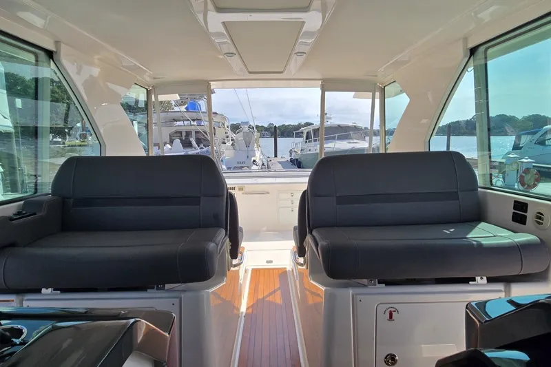 Slide: The Image of Interior view of 2016 Tiara Yachts Q44 with luxurious seating and scenic marina backdrop. - 48