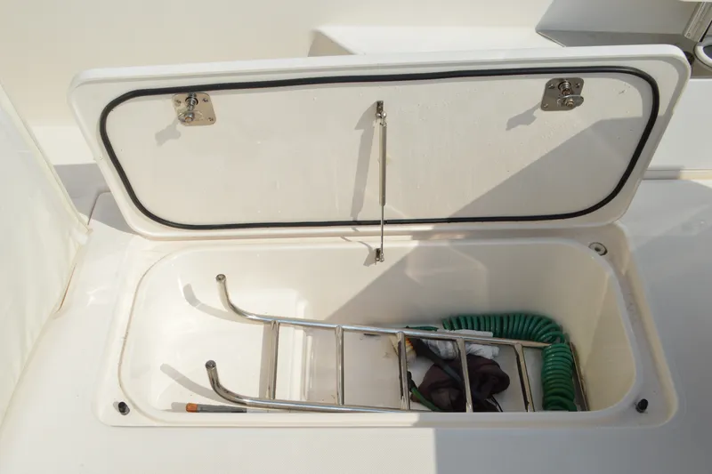 Slide: The Image of Open storage compartment on 2016 Tiara Yachts Q44, containing a ladder and hose. - 23