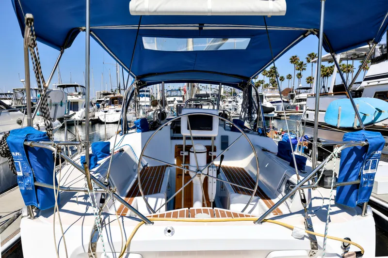 Slide: The Image of 1990 Jeanneau Sun Magic 44 sailboat docked at marina, featuring spacious cockpit and blue canopy. - 19
