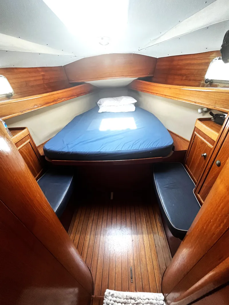 Slide: The Image of Cozy cabin interior of 1990 Jeanneau Sun Magic 44 sailboat with wooden finish and blue bedding. - 9