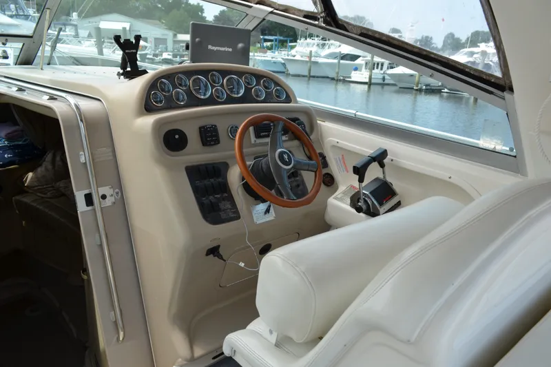 Slide: The Image of 1998 Sea Ray 290 Sundancer helm with steering wheel and control panel, docked at marina. - 33