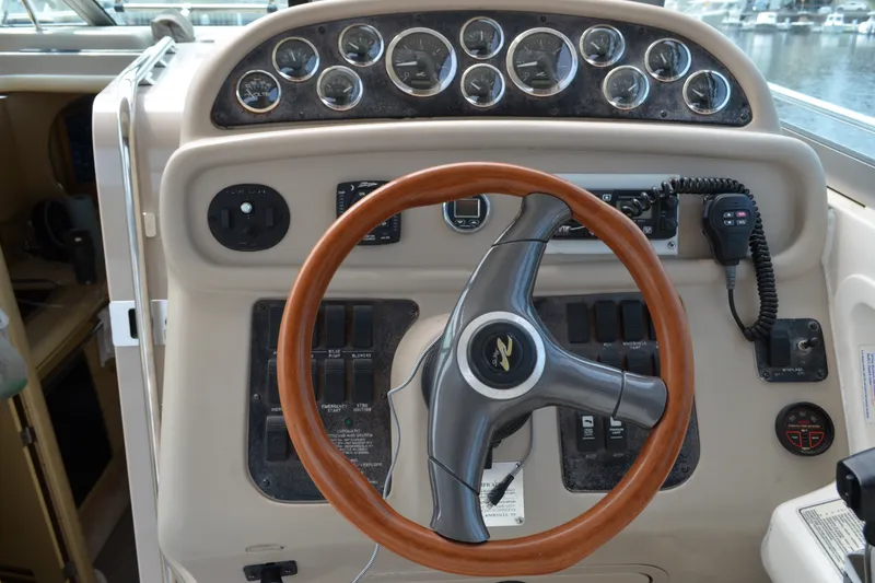 Slide: The Image of 1998 Sea Ray 290 Sundancer helm with wooden steering wheel and control panel. - 35