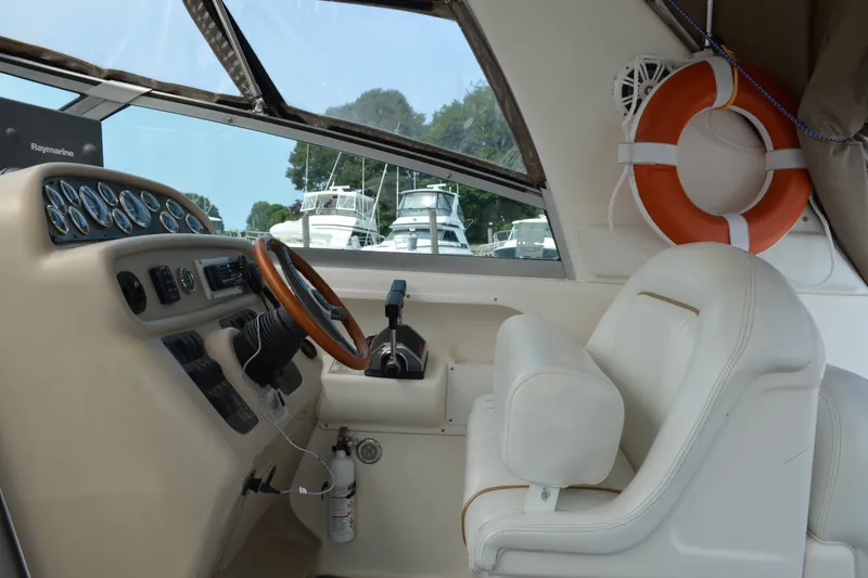 Slide: The Image of 1998 Sea Ray 290 Sundancer helm with steering wheel, gauges, and life preserver. - 34