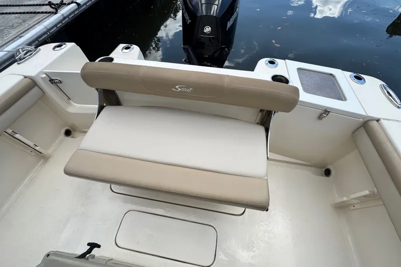 Slide: The Image of 2022 Scout 215 XSF boat interior with seating and motor, docked on water. - 44