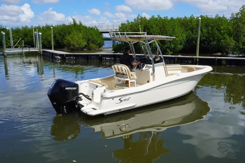 Slide: The Image of 2022 Scout 215 XSF boat with Mercury engine on calm water near dock. - 9
