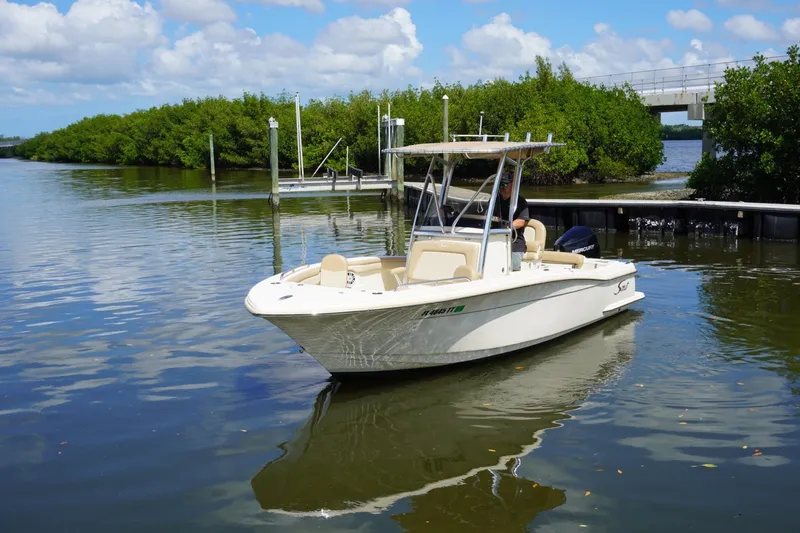 Slide: The Image of 2022 Scout 215 XSF boat cruising on a calm river near lush greenery. - 5