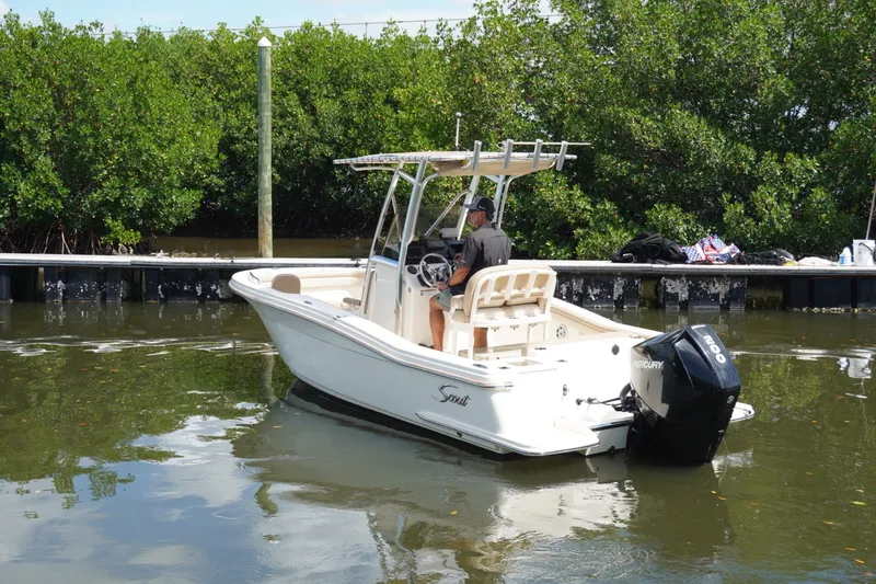 Slide: The Image of 2022 Scout 215 XSF boat with Mercury engine near dock, surrounded by greenery. - 12