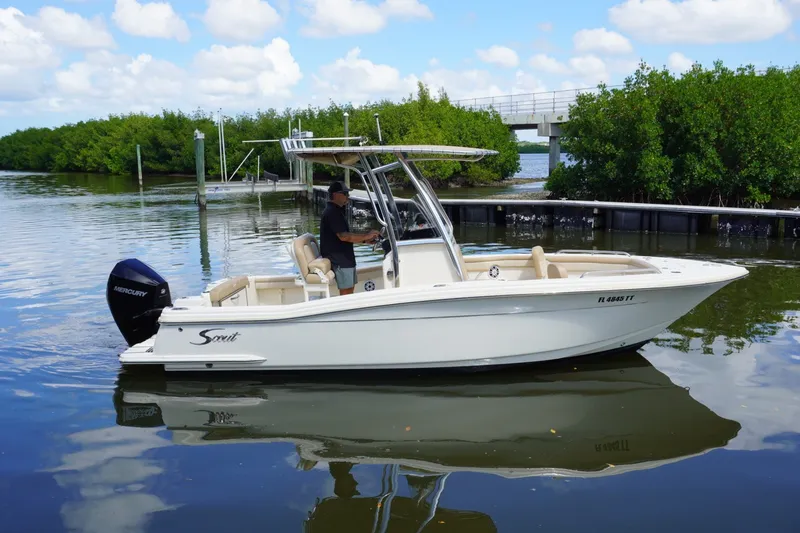 Slide: The Image of 2022 Scout 215 XSF boat on calm water near lush greenery and a bridge. - 6