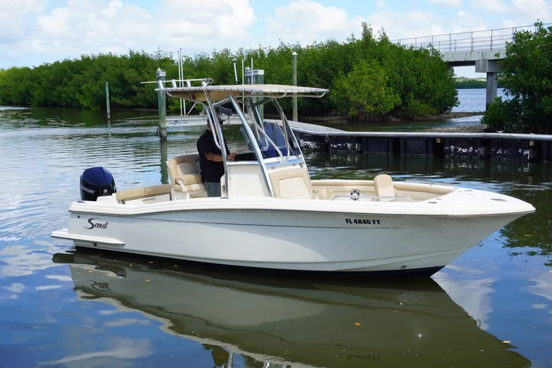 Slide: The Image of 2022 Scout 215 XSF boat on calm water near a dock and greenery. - 7