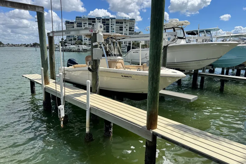 Slide: The Image of 2022 Scout 215 XSF boat docked on a sunny waterfront with buildings in the background. - 49